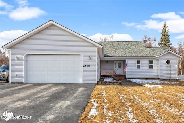 ranch-style house with aphalt driveway, roof with shingles, and an attached garage