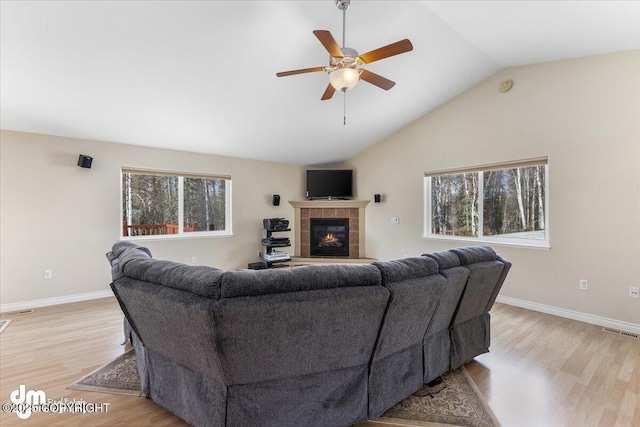 living room with a tiled fireplace, light wood finished floors, plenty of natural light, and visible vents