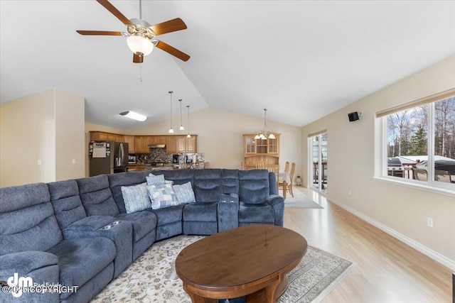 living room featuring light wood finished floors, baseboards, vaulted ceiling, and a ceiling fan