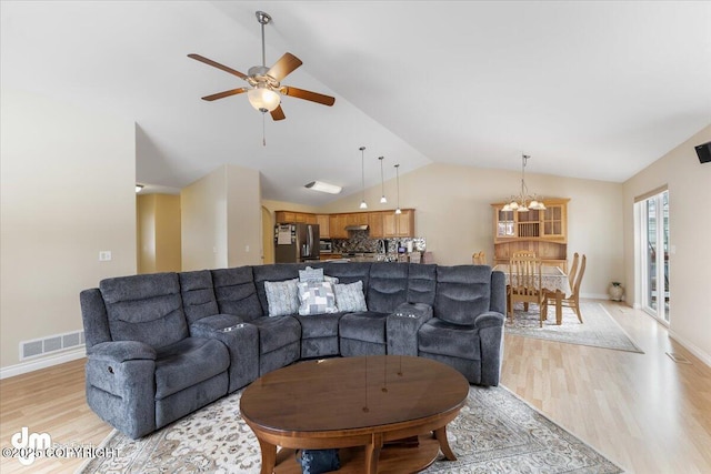 living room featuring lofted ceiling, visible vents, light wood-style floors, baseboards, and ceiling fan with notable chandelier