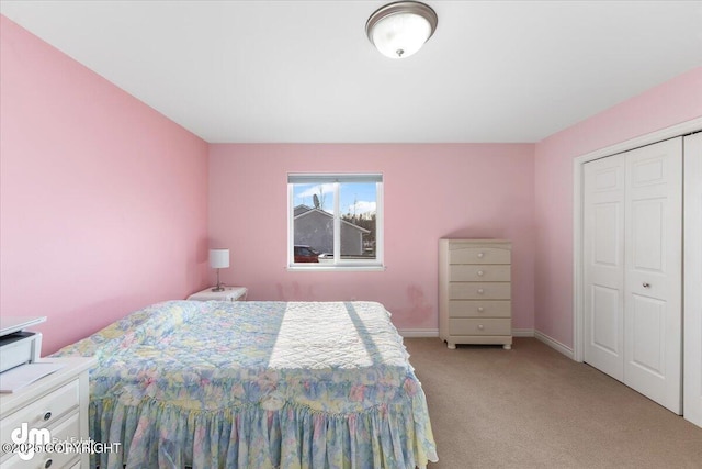 bedroom with baseboards, a closet, and light colored carpet