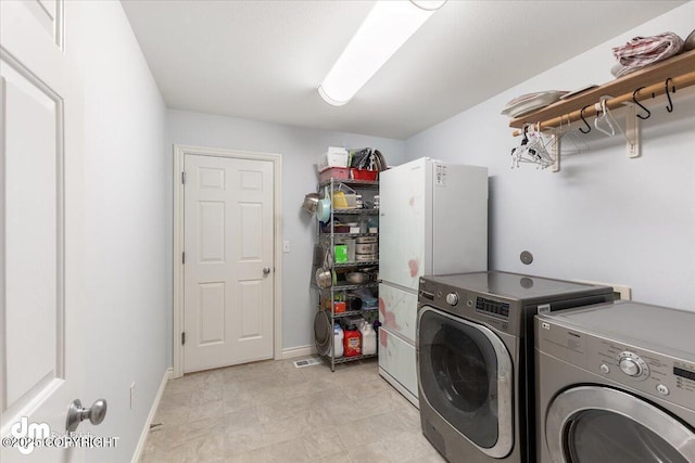 clothes washing area with laundry area, washing machine and dryer, and baseboards