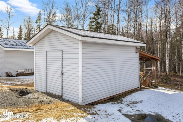 snow covered structure featuring an outdoor structure and a shed