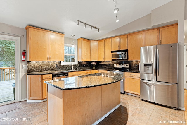 kitchen with dark stone counters, lofted ceiling, appliances with stainless steel finishes, light brown cabinetry, and backsplash