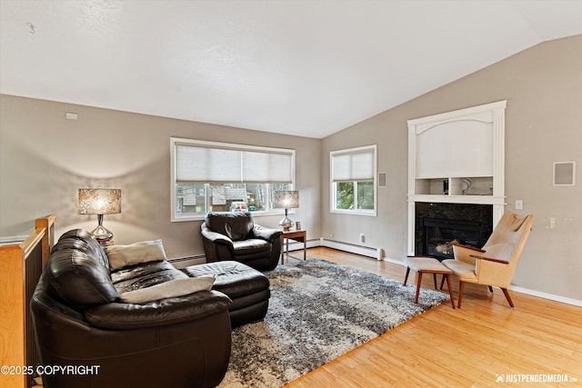 living room with lofted ceiling, a baseboard radiator, a premium fireplace, baseboard heating, and light wood-style floors