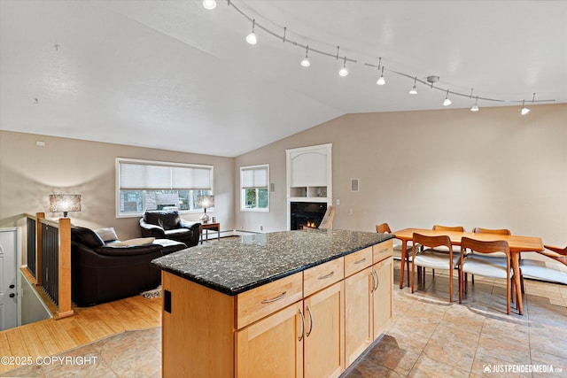 kitchen with lofted ceiling, open floor plan, a center island, and a lit fireplace