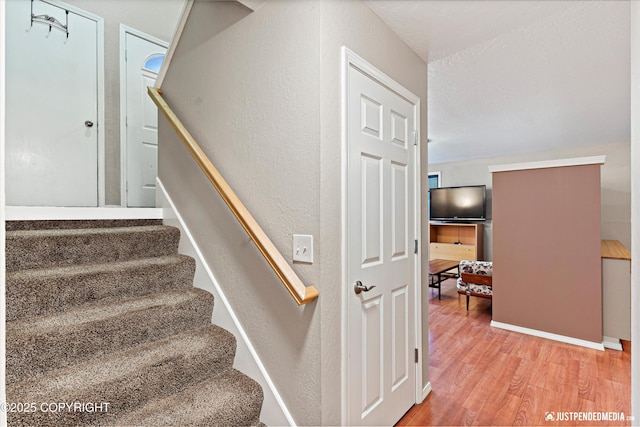 stairway with a textured wall and wood finished floors