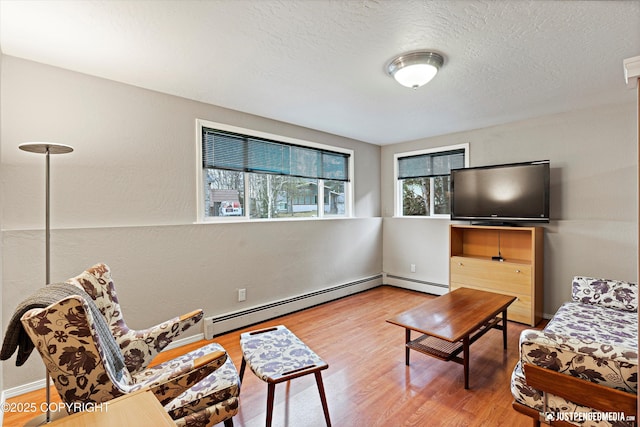 interior space with a textured ceiling, baseboard heating, and wood finished floors