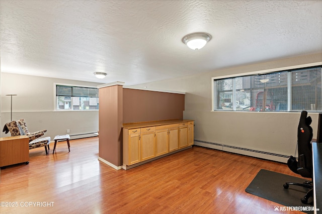 office space featuring a textured ceiling, baseboard heating, and light wood-style floors