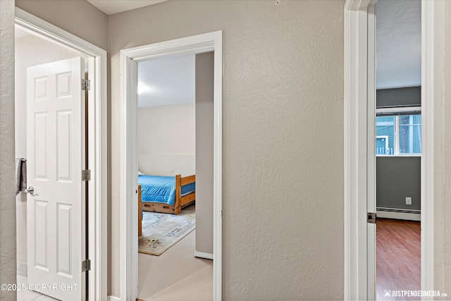 hallway with a baseboard radiator and a textured wall