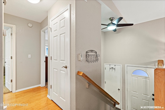 corridor featuring an upstairs landing, light wood-type flooring, and baseboards