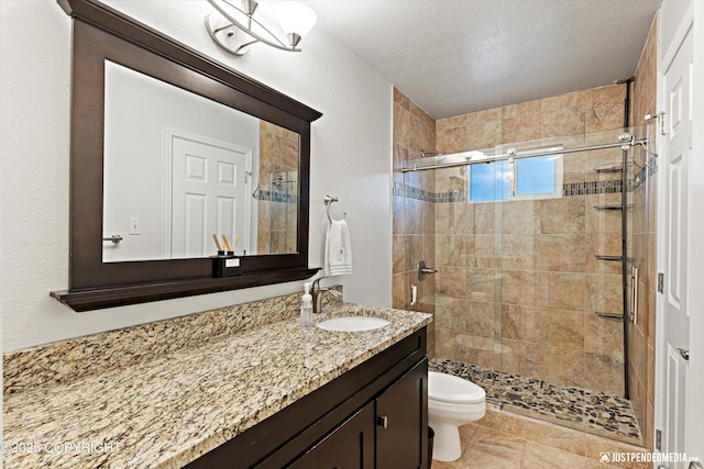 full bath featuring a textured ceiling, a stall shower, vanity, and toilet