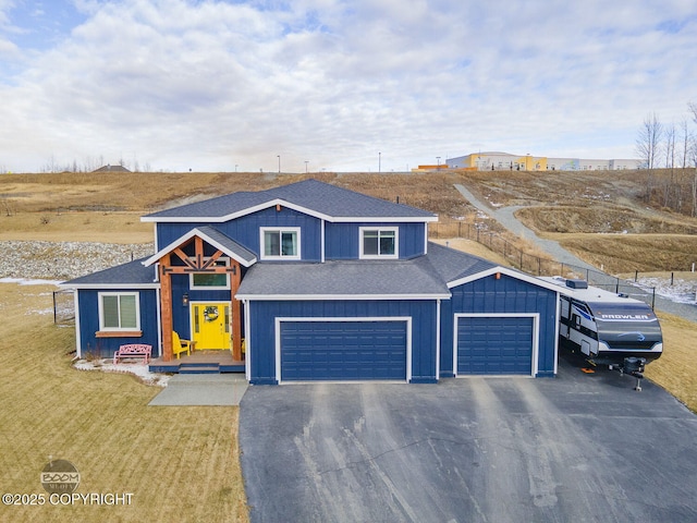 view of front of property featuring a shingled roof, fence, driveway, board and batten siding, and a front yard