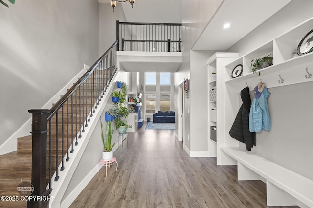 mudroom featuring recessed lighting, baseboards, a high ceiling, and wood finished floors