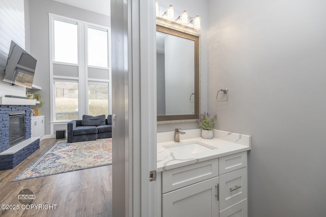 bathroom with a fireplace, vanity, and wood finished floors