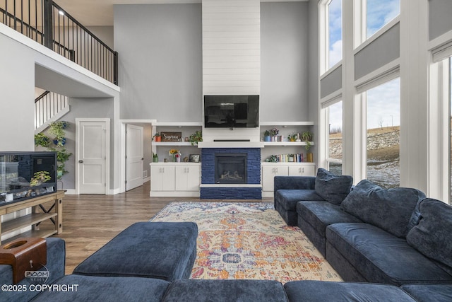 living area featuring a high ceiling, wood finished floors, and a glass covered fireplace