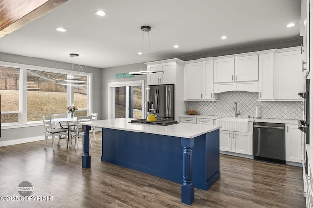 kitchen with a sink, white cabinetry, appliances with stainless steel finishes, decorative backsplash, and decorative light fixtures