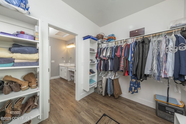 walk in closet with attic access, lofted ceiling, and wood finished floors