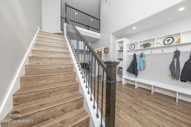 stairs featuring a high ceiling, wood finished floors, and recessed lighting