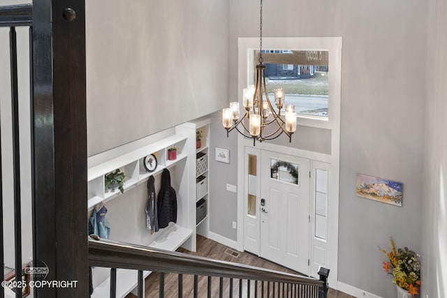 foyer with a notable chandelier, baseboards, and wood finished floors