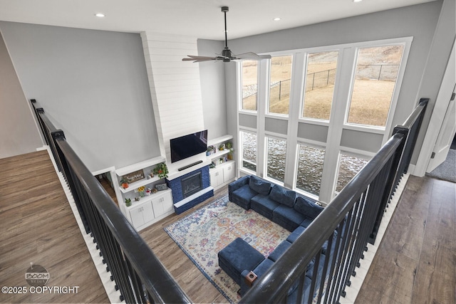 living room featuring recessed lighting, a fireplace, a high ceiling, and wood finished floors