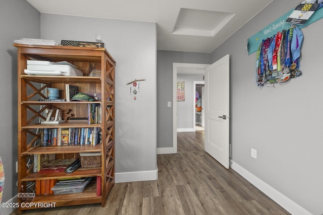 hall with attic access, baseboards, and wood finished floors