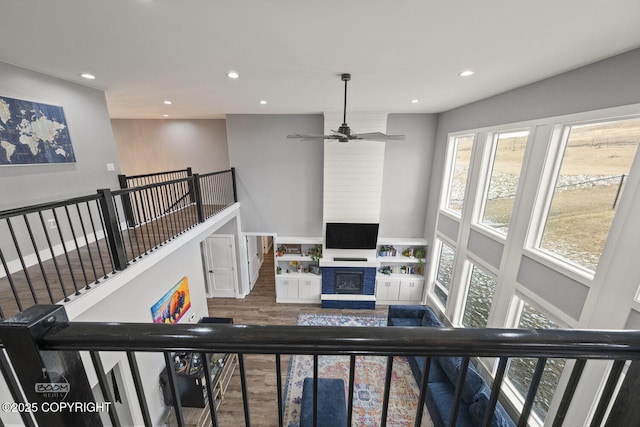 interior space featuring a high ceiling, a fireplace, wood finished floors, and recessed lighting