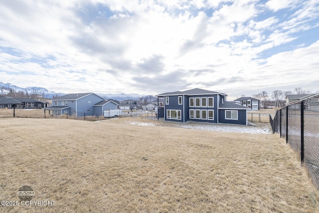 back of property featuring a mountain view, a lawn, fence, and a residential view