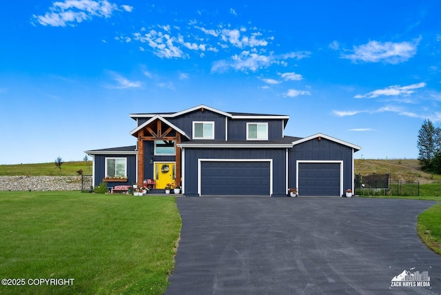 view of front of house featuring aphalt driveway, an attached garage, fence, a front lawn, and board and batten siding