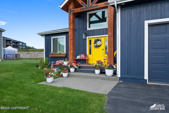 entrance to property featuring board and batten siding and a yard