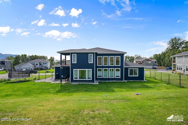 back of house featuring a balcony, fence, a yard, a trampoline, and a patio area