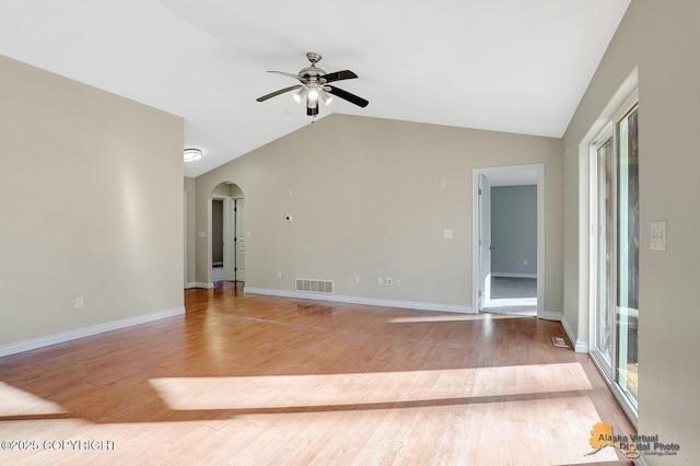 unfurnished room with arched walkways, visible vents, vaulted ceiling, and wood finished floors