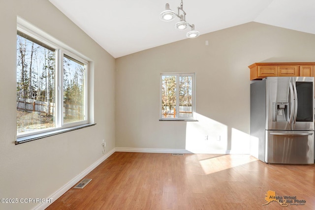 unfurnished dining area with lofted ceiling, a healthy amount of sunlight, light wood-type flooring, and baseboards