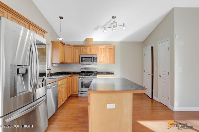 kitchen featuring lofted ceiling, a sink, stainless steel appliances, light wood-style floors, and dark countertops