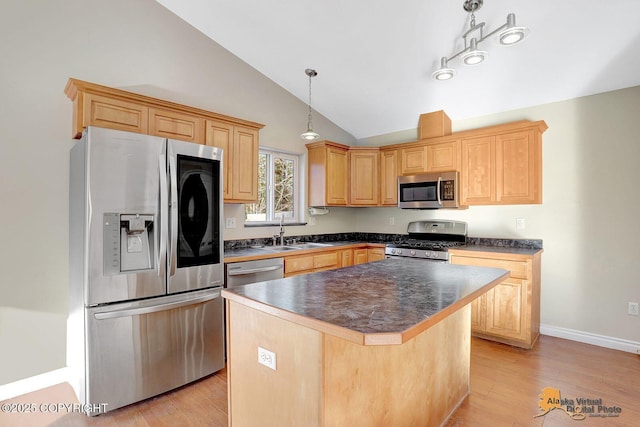 kitchen with dark countertops, light wood-type flooring, vaulted ceiling, stainless steel appliances, and a sink