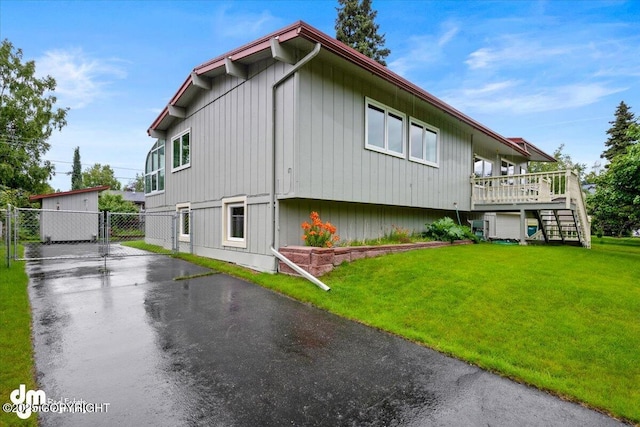 view of side of home featuring stairs, a gate, a lawn, and fence