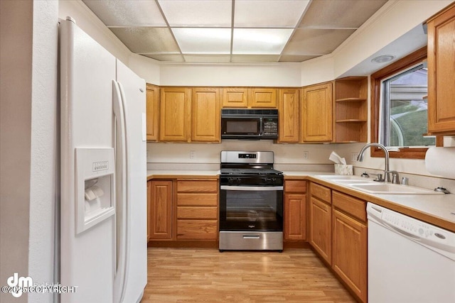 kitchen with white appliances, light countertops, light wood-style floors, and a sink