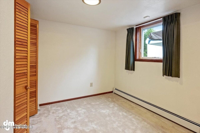 empty room with baseboards, baseboard heating, and light carpet