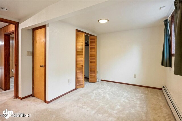 unfurnished bedroom featuring light carpet, baseboards, a closet, and a baseboard radiator