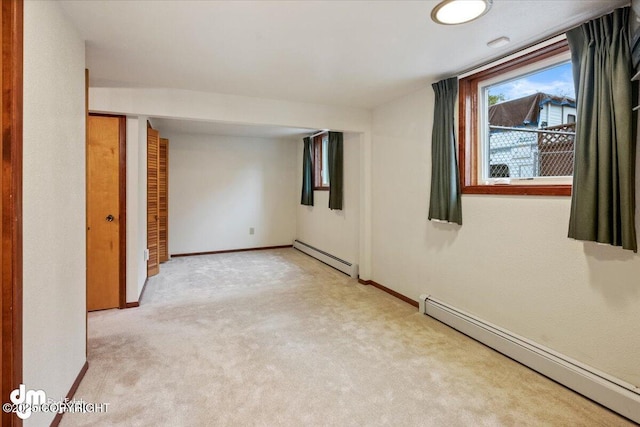 empty room featuring a baseboard radiator, light carpet, and baseboards