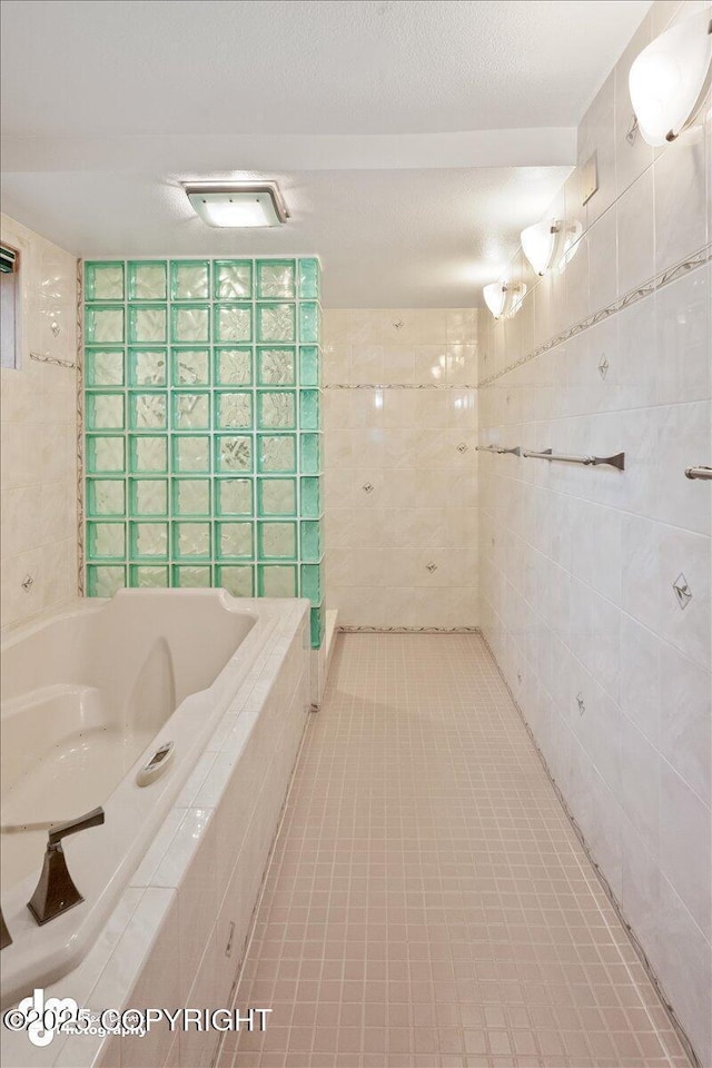 full bathroom featuring tile patterned floors, a relaxing tiled tub, a textured ceiling, and tile walls