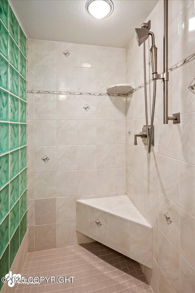 full bathroom featuring a tile shower and a textured ceiling