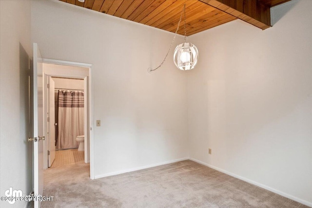 spare room featuring baseboards, light carpet, and wooden ceiling