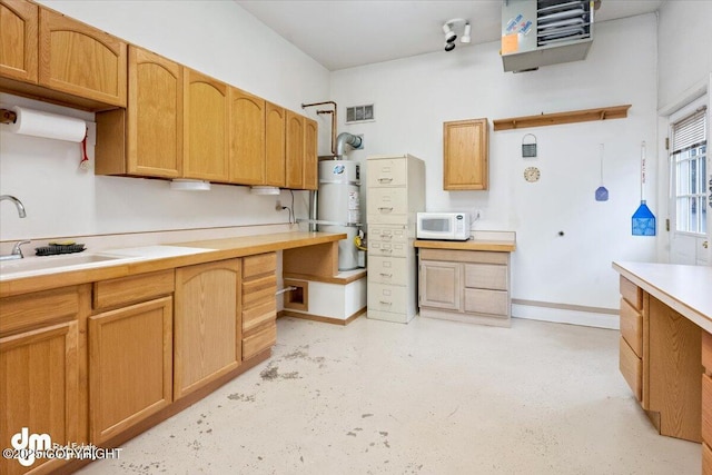 kitchen featuring visible vents, a sink, strapped water heater, light countertops, and white microwave