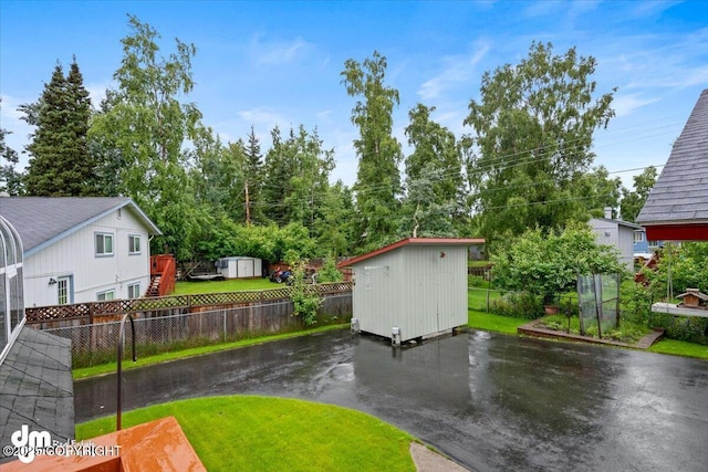 view of yard featuring a storage shed, an outdoor structure, and fence