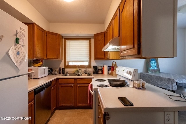408 Haller St, Kenai, AK 99611 - kitchen with white appliances, under cabinet range hood, a sink, light countertops, and brown cabinets
