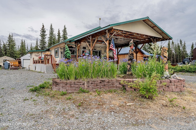 view of front of home with gravel driveway, a wooden deck, and an outdoor structure