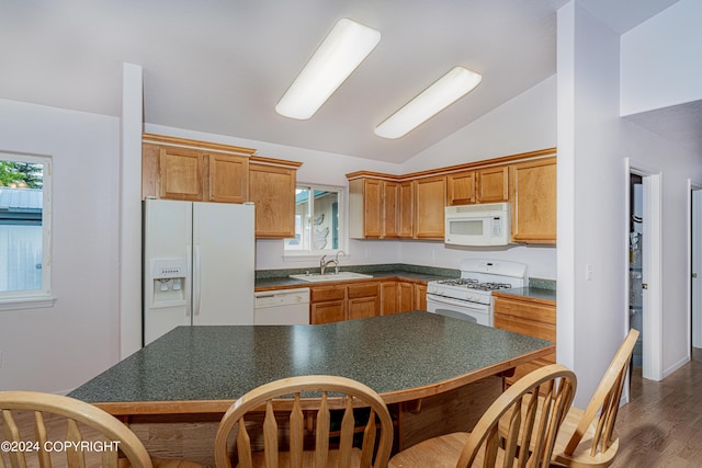 kitchen with dark wood-style flooring, dark countertops, vaulted ceiling, a sink, and white appliances