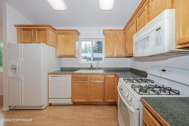 kitchen with dark countertops, white appliances, light wood-style floors, and a sink