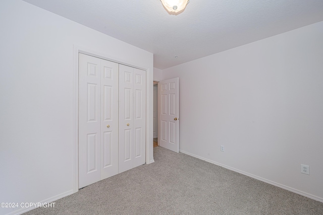 unfurnished bedroom with carpet floors, a closet, and baseboards